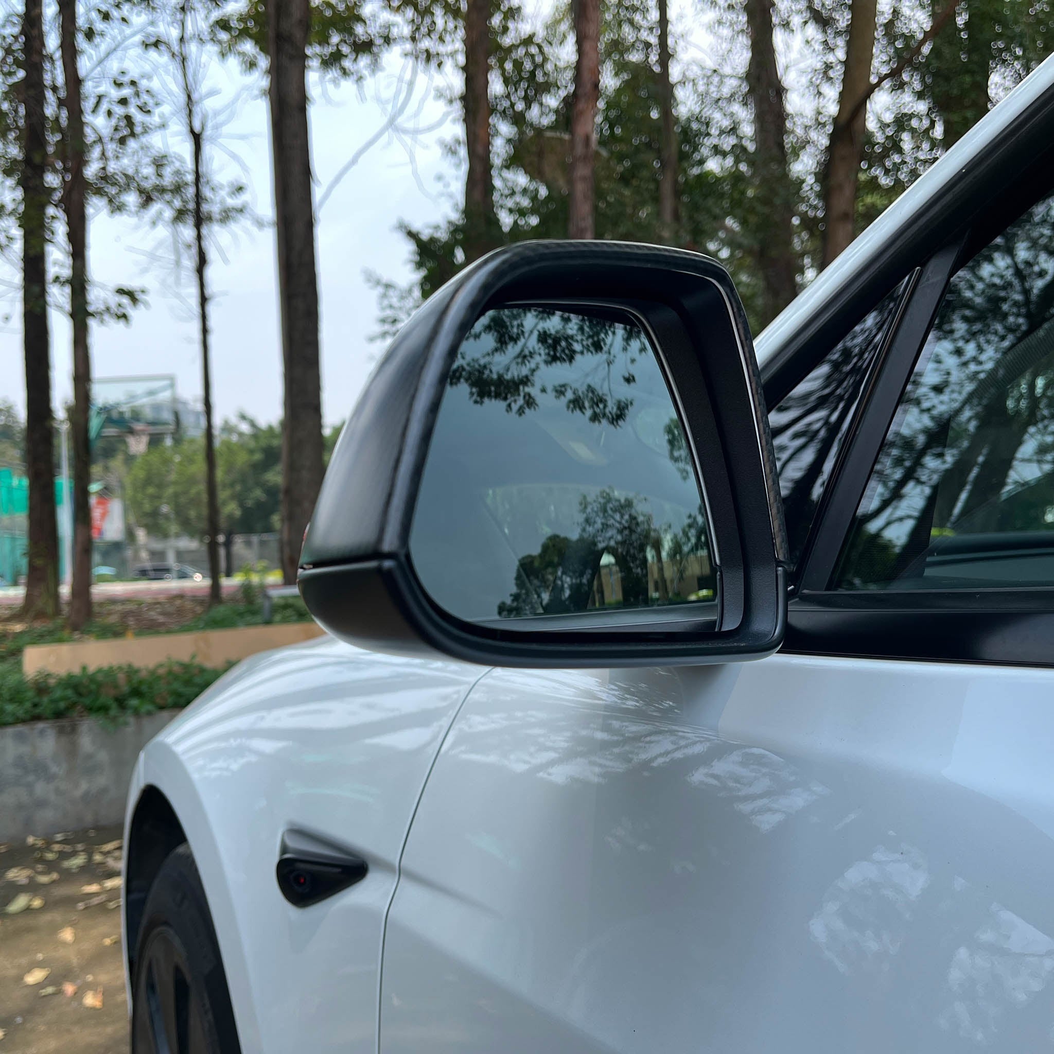 Rear view of a Real Carbon Fiber Mirror Covers installed on a 2024+ Tesla Model 3 Highland
